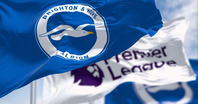 Brighton, UK, Dec. 23 2023: Brighton football club and Premier League flags waving in the wind on a clear day. Illustrative editorial 3d illustration render. Rippled fabric