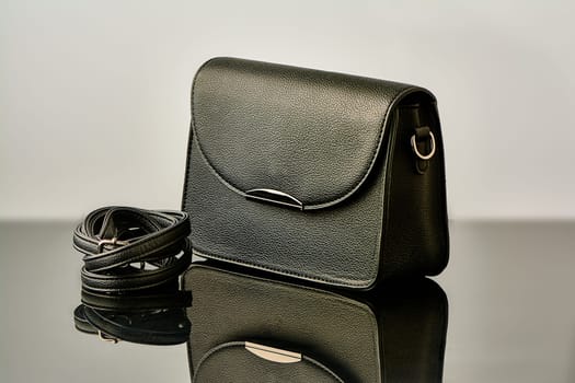 A black handbag stands on black glass. High quality photo