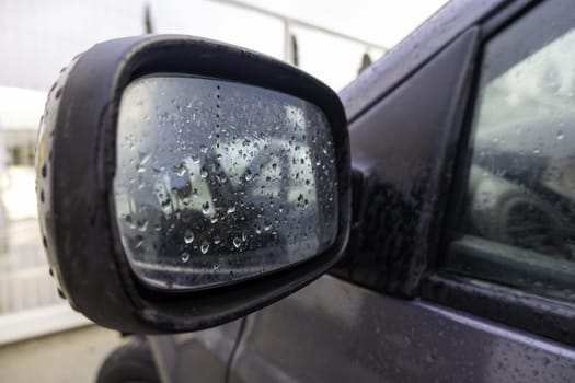 Detail of a wet car mirror on a cold and rainy winter day