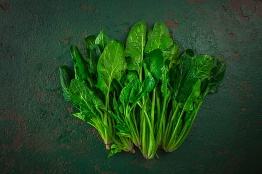 Bunch of fresh organic spinach on green background.