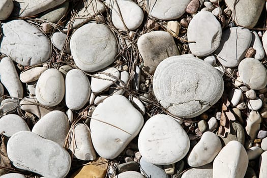 Sea pebbles of different shapes with small particles of dirt on the surface close-up on the street top view