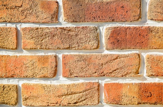 A brick wall made of cracked decorative orange bricks in close-up. Texture or background