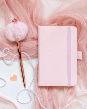 Pink hardcover notebook near hearts and vase on white table top view. Romantic mockup for Wedding, Valentines, Spring or Mothers day