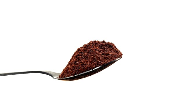 Ground coffee powder in a stainless steel teaspoon isolated on a white background