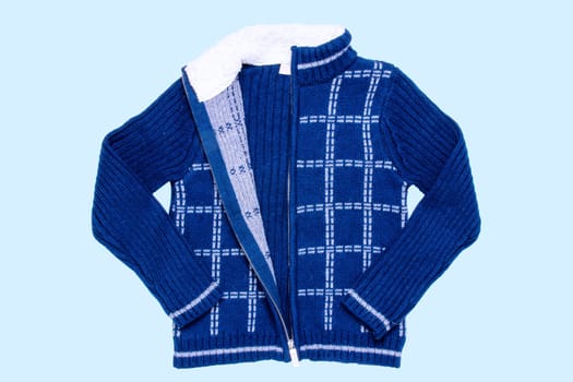 Autumn and winter jacket. A dark blue woolen knitted cardigan or pullover with a white checkered pattern on light blue background. Kids cozy warm jumper or  sweater fashion.