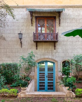 Charming Mediterranean architecture house with a bright blue door and a small balcony above. The house is made of stone brick