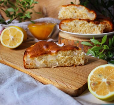 A piece of apple pie on a wooden board with lemon slices and honey on a background of green twigs and wooden blocks