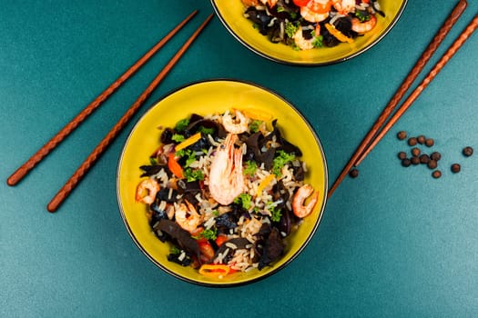 Traditional Chinese food, fried rice with shrimp or prawns and mushrooms on old rustic wooden table.