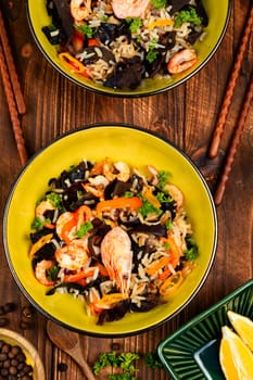 Traditional Chinese food, fried rice with shrimp or prawns and mushrooms on old rustic wooden table.