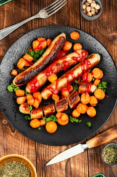 Grilled turkey sausages with roasted carrots on the plate. Copy space.