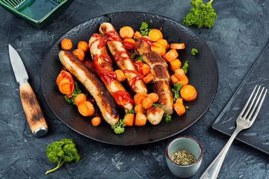 Baked or grilled turkey sausages with roasted carrots on the plate. German BBQ menu.
