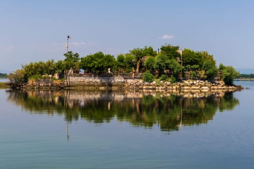 Grado, Italy - June 28th, 2019: One of the many little islands in the lagoon of Grado that offer a nice weekend escape in a small house and garden surrounded by the water or serve as fishermens huts.