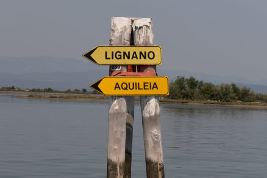 Grado, Italy - June 28th, 2019: Signposts in the lagoon of Grado showing the boat way to the next cities.