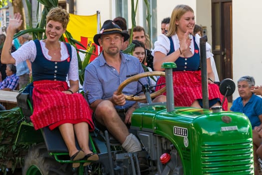 Villach, Austria - August 3th, 2019: Participants riding a tractor at the procession of 'Villacher Kirchtag', the largest traditional folk festival in Austria.
