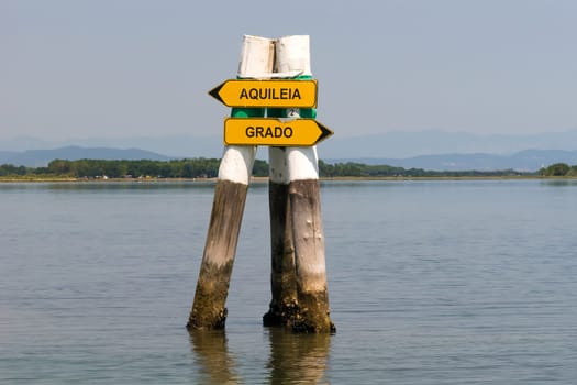 Grado, Italy - June 28th, 2019: Signposts in the lagoon of Grado showing the boat way to the next cities.