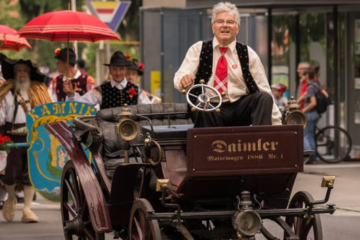 Villach, Austria - August 3th, 2019: An older man riding a oldtimer at the procession of 'Villacher Kirchtag', the largest traditional folk festival in Austria.