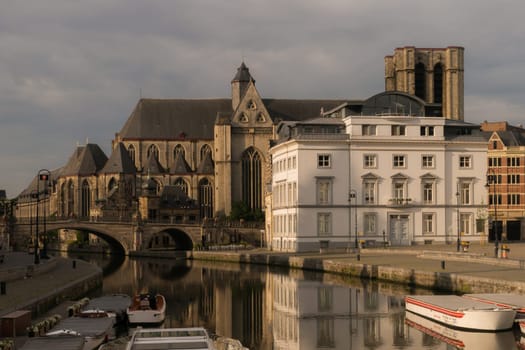 Ghent, Belgium - June 10th, 2019: A pleasant morning view of medieval Ghent old town along river Leie to Saint Michael's Church.