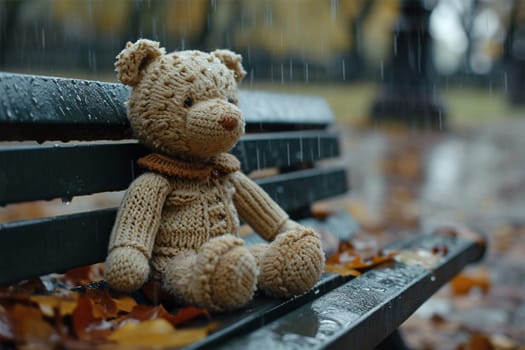 Lonely bear in a knitted beige sweater on a park bench, lost and alone in a rainy park. Loneliness concept, International Missing Children's Day