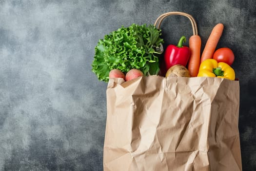 Eco-friendly shopping bag with assorted fresh vegetables on a gray background.