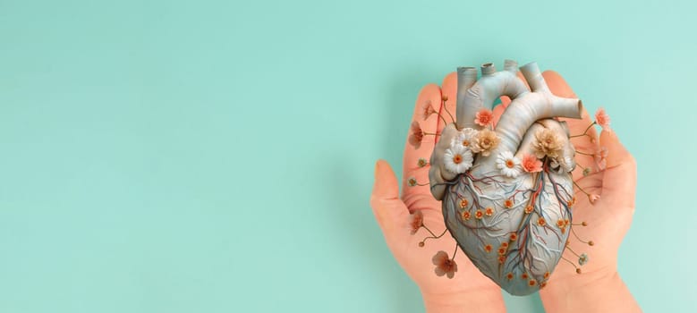 Holding human heart with flowers, love and emotion concept, good hearted person, help and charity, organ donation