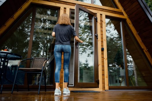 Back view of a woman opening the door of a country house and enters inside