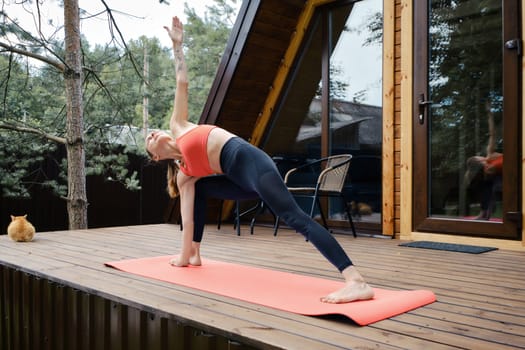 Flexible woman does the half moon yoga pose outdoors
