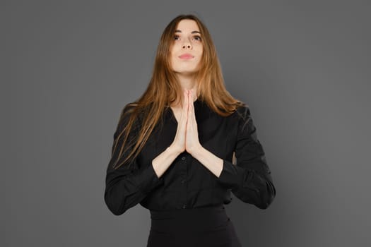 Woman holds hands in praying gesture, looking up
