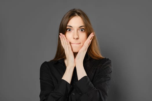 Studio portrait of surprised young woman on grey background