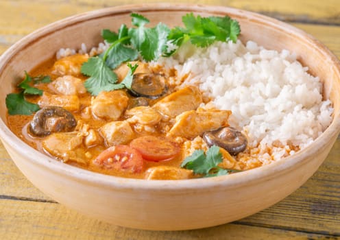 Bowl of chicken red curry on wooden background