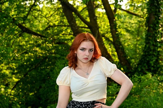 Portrait of a young girl in green nature, looking  at the camera