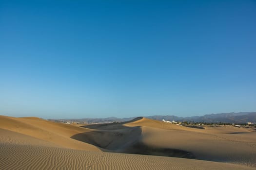 Sand dunes of Maspalomas with a view to the town of Playa del Inglés on the Canary Island of Gran Canaria, Spain, Europe. The huge sand dunes resemble a small desert and are a nature reserve.