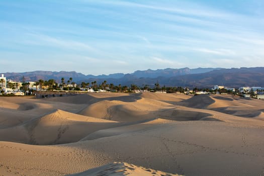 Sand dunes of Maspalomas with a view to the town of Playa del Inglés on the Canary Island of Gran Canaria, Spain, Europe. The huge sand dunes resemble a small desert and are a nature reserve.