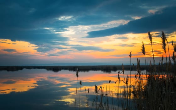 Dramatic sunset at the Lake Neusiedlersee in Austria with colorful orange and red illuminated cloudy sky