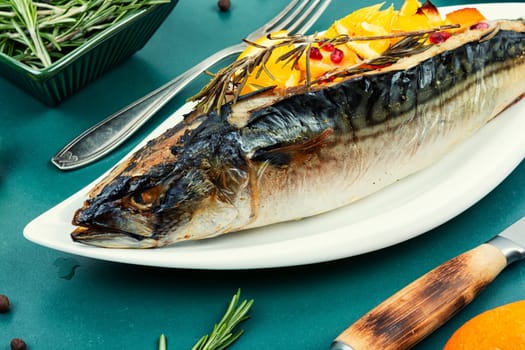 Mackerel fish baked with oranges and rosemary on a vintage wooden background.