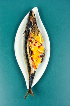 Mackerel fish baked with oranges and rosemary on a vintage wooden background.