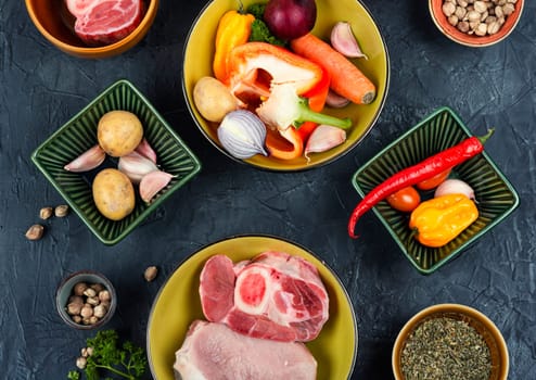 Raw piece uncooked meat and different vegetables on the kitchen table. Set of ingredients for soup. Top view, flat lay.