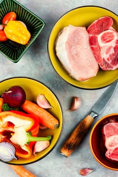 Raw piece uncooked meat and different vegetables on the kitchen table. Set of ingredients for soup. Top view, flat lay.