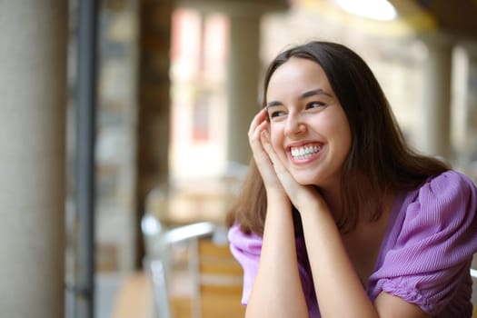 Happy woman laughing alone in a bar looking at side