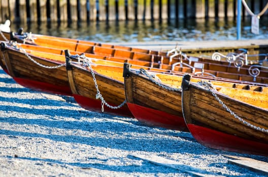 Wooden boats with chains standing on the beach in a row.