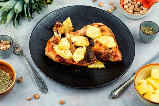 Tasty chicken legs fried with pineapple slices. Barbecue chicken meat on a plate.