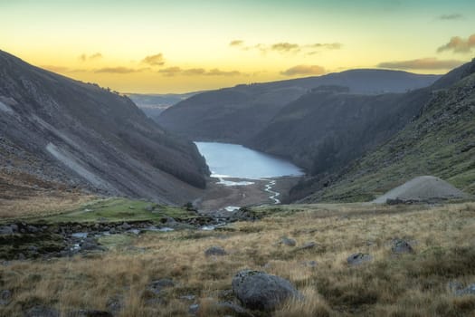 Sunset at scenic Glendalough lake, river, valley and forest. Hiking in beautiful autumn Wicklow Mountains, Ireland