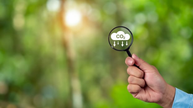 A clean and friendly environment without carbon dioxide emissions, Hand holding magnifying glass with CO2 reduction icon inside, carbon credit to limit global warming from climate change, carbon neutral.