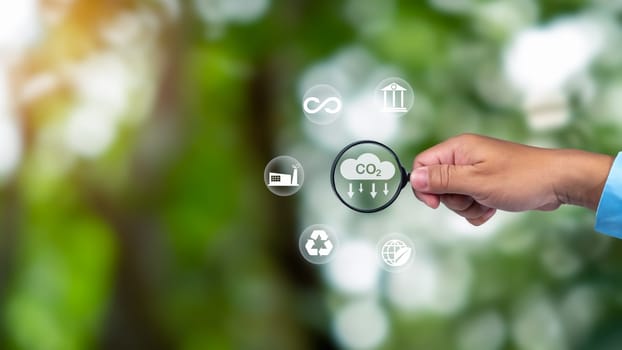 A clean and friendly environment without carbon dioxide emissions, Hand holding magnifying glass with CO2 reduction icon inside, carbon credit to limit global warming from climate change, carbon neutral.
