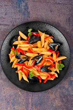 Macaroni or pasta vongole with mussels in the shell, clams on a stylish dark plate. Mediterranean cuisine.
