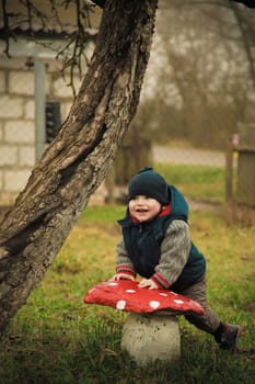 A little boy stands on the street posing near a stone mushroom on a summer day