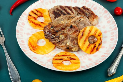 Grilled juicy steak and ananas. Delicious juicy roasted pork steak with pineapple rings.