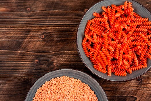 Raw and dry macaroni. Uncooked vegan pasta or macaroni, red lentil fusilli on the plate. Copy space.