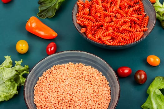Raw and dry macaroni. Uncooked vegan pasta or macaroni, red lentil fusilli on the plate. Copy space.