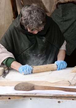 Cracow, Poland - April 11, 2023: Woman hands rolling out dough in knight camp at the festival of historical reconstruction