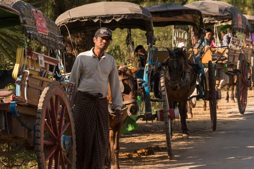Inwa, Myanmar - January 17th, 2019: A long row of horse buggies that are waiting for passengers at a popular temple in Inwa near Mandalay.